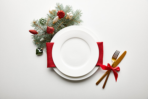 top view of festive Christmas table setting on white background with decorated pine branch