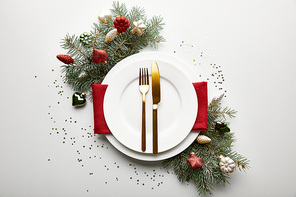 top view of festive Christmas table setting on white background with decorated pine branch and confetti