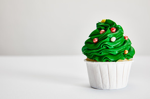 tasty Christmas tree cupcake on white surface isolated on grey