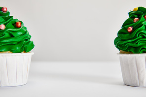 tasty Christmas tree cupcakes on white surface isolated on grey with copy space