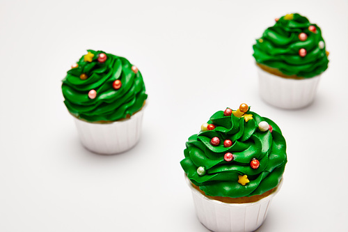 selective focus of tasty Christmas tree cupcakes on white surface