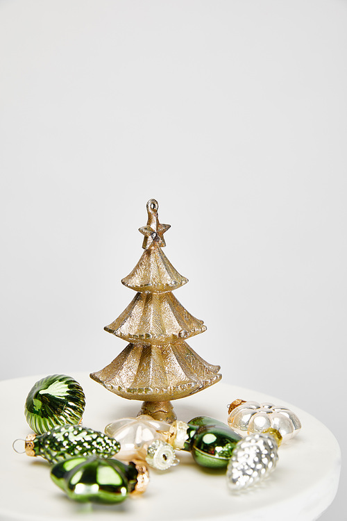 shiny Christmas tree and baubles on white surface isolated on grey