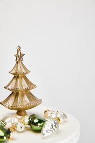 shiny Christmas tree and baubles on white surface isolated on grey