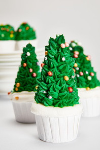 delicious Christmas tree cupcakes on white surface isolated on grey