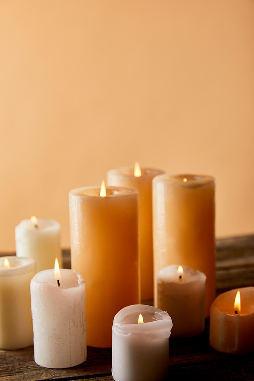 close up of burning candles on wooden table on beige