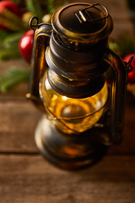 close up of decorative vintage oil lamp with spruce branches and christmas balls on wooden table
