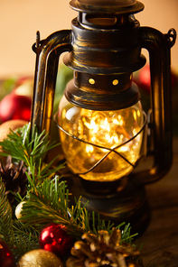 close up of decorative vintage oil lamp with blurred lights, spruce branches and christmas balls