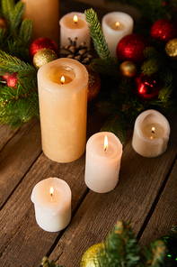 burning candles with spruce branches and christmas balls on wooden table
