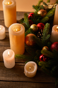 burning candles with spruce branches and christmas balls on wooden table