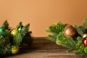 decorative spruce branches with christmas balls on wooden table on beige