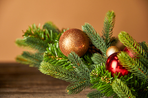 festive spruce branches with christmas balls on wooden table on beige