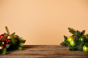 spruce branches with christmas balls on wooden table on beige