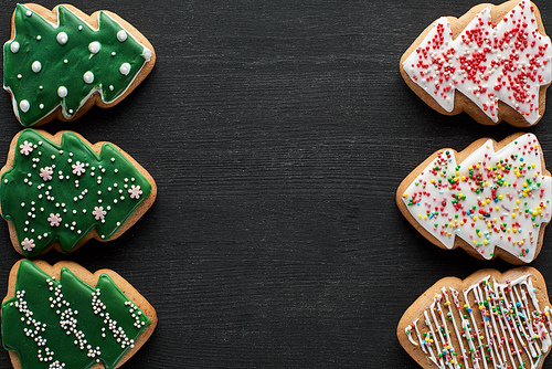 flat lay with delicious glazed Christmas tree cookies on black background with copy space