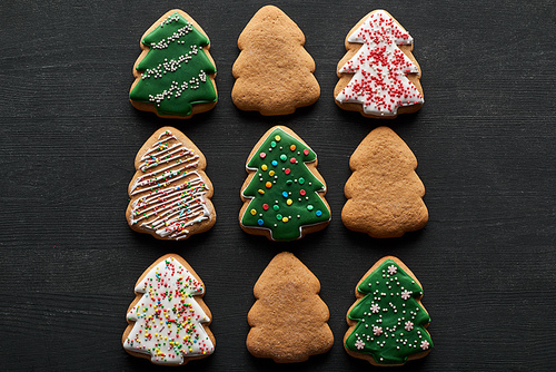 flat lay with delicious glazed Christmas tree cookies on black background