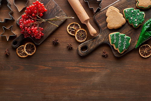 top view of Christmas cookies near viburnum and spices on wooden table