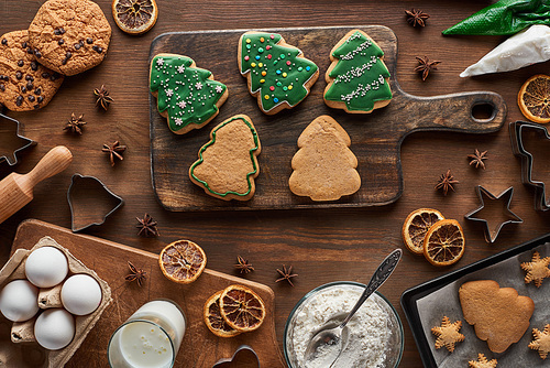 top view of Christmas tree cookies near ingredients on wooden table