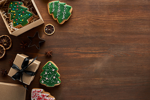 top view of Christmas tree cookie in gift box on wooden table with dried citrus and anise