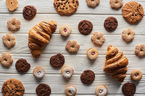 top view of sweet cookies and croissants on white wooden table