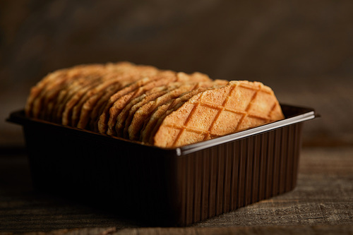 selective focus of delicious thin waffles in container on wooden table