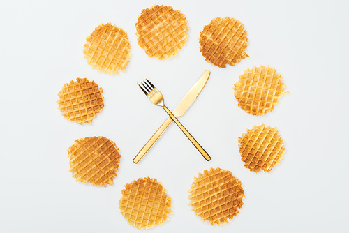 top view of waffles with fork and knife in middle isolated on white