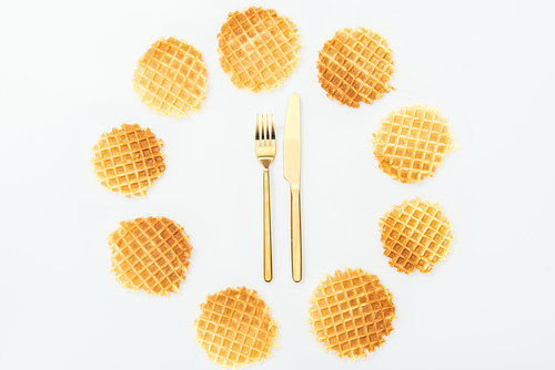 top view of waffles in circle with fork and knife in middle isolated on white
