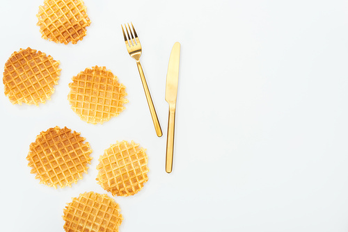 top view of golden cutlery near waffles isolated on white