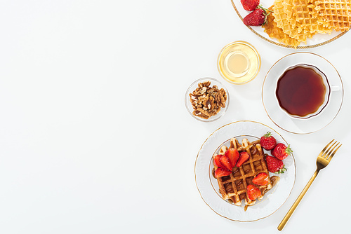 top view of strawberries, waffles and tea on white