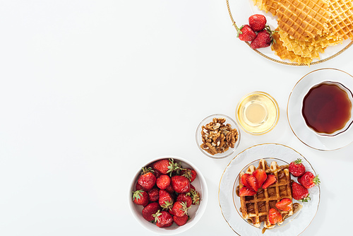 top view of tasty breakfast with strawberries and waffles on white