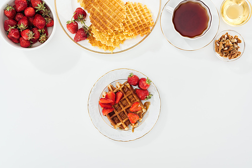 top view of delicious breakfast with waffles, strawberries and tea on white