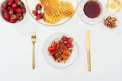 top view of served breakfast with waffles and strawberries on white