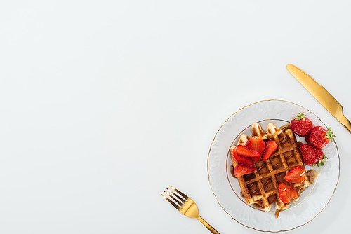 top view of plate with waffles near fork and knife on white