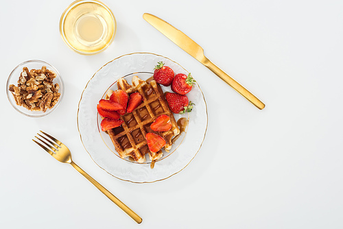 flat lay with waffles and strawberries on plate near bowls on white