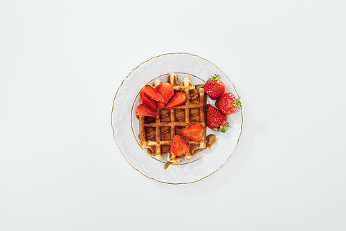 top view of small plate with strawberries on waffle on white