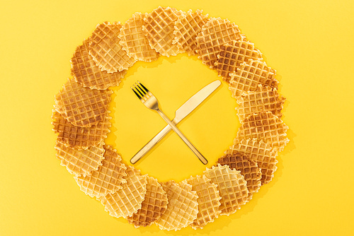 top view of waffles in circle with fork and knife in middle on yellow