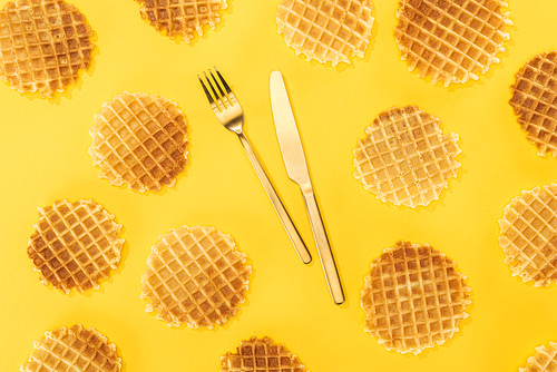 top view of waffles with cutlery in middle isolated on yellow