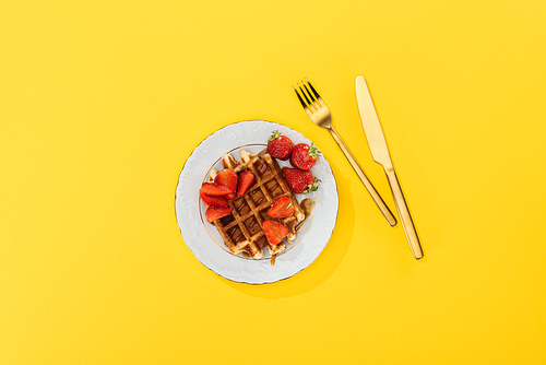top view of plate with tasty waffle and strawberries for breakfast on yellow