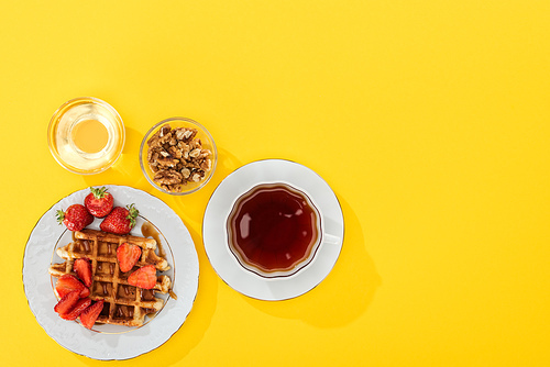 top view of waffles, berries, honey and nuts on yellow