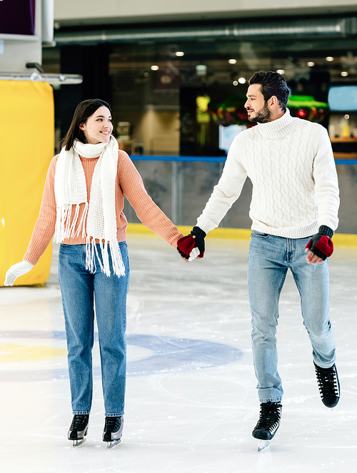 beautiful happy couple holding hands and spending time on skating rink