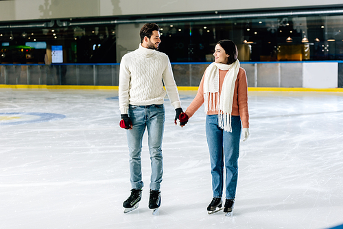 beautiful happy couple holding hands on skating rink