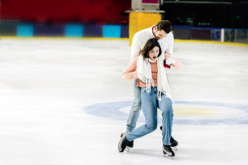 young handsome man catching falling woman on skating rink