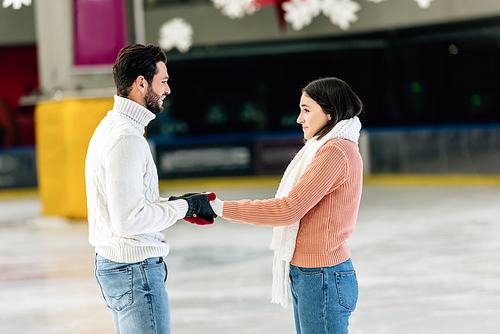 beautiful happy couple holding hands on skating rink