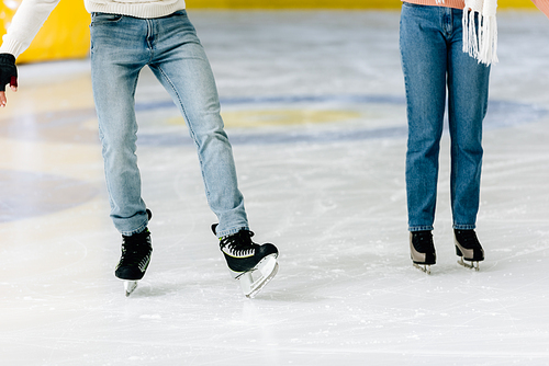 cropped view of young woman teaching man to skate on a rink