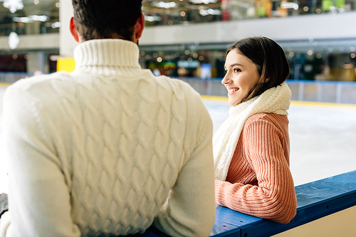 young couple in sweaters spending time on skating rink