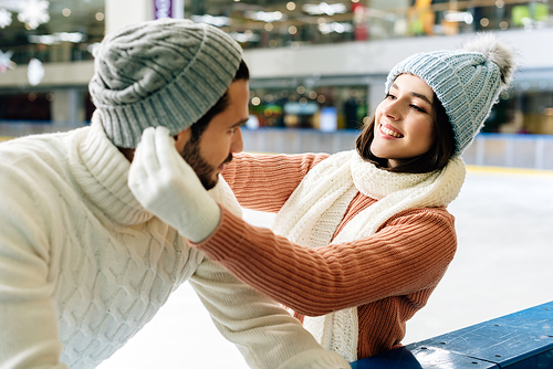 young smiling couple wearing hats on skating rink