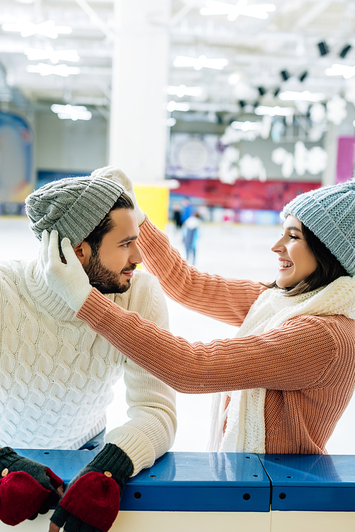 happy smiling couple wearing hats on skating rink