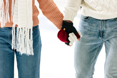 cropped view of couple in gloves holding hands on skating rink