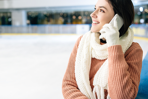 attractive smiling girl talking on smartphone on skating rink