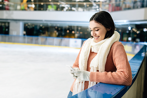 beautiful happy girl using smartphone on skating rink