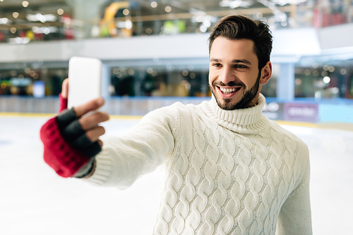 cheerful man making video call on smartphone on skating rink