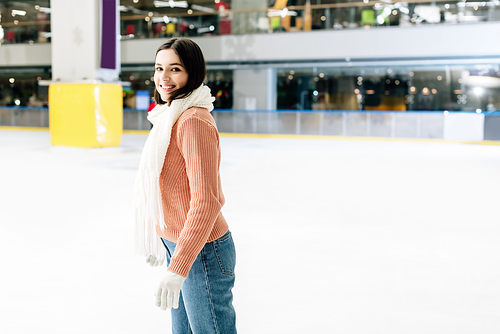 beautiful happy girl in sweater and scarf skating on rink